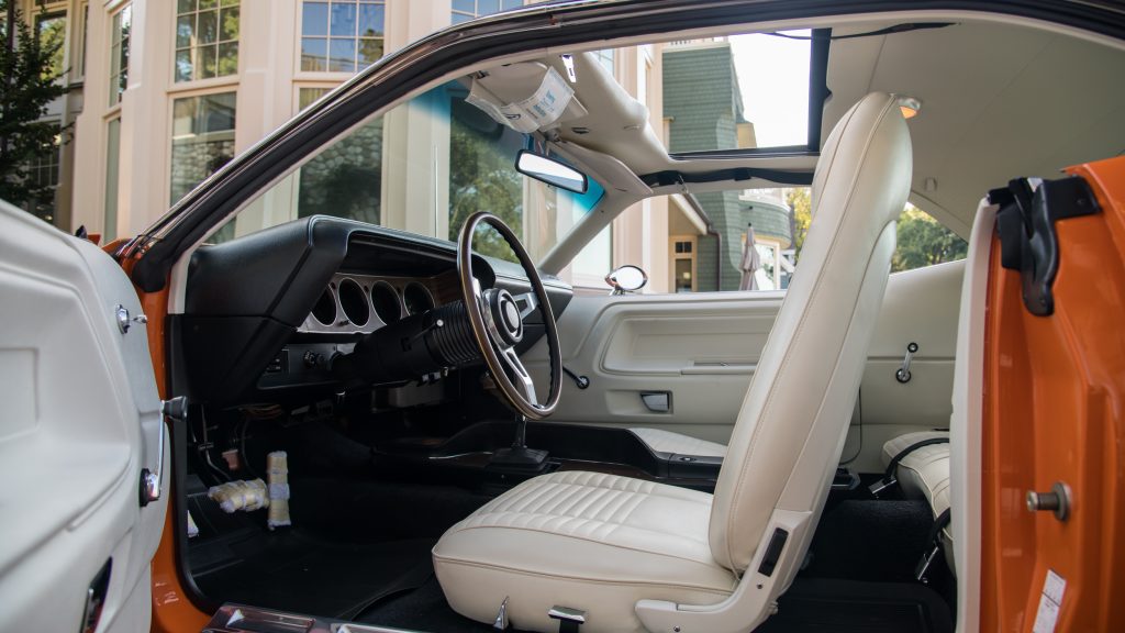 The driver door is open revealing the white interior of the Dodge Challenger