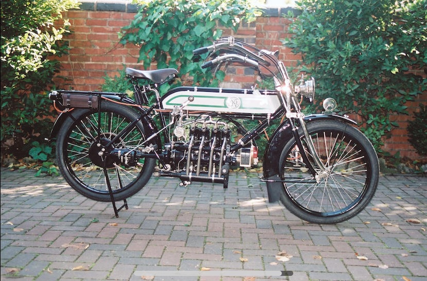 A silver-tanked 1913 FN Four in front of a garden wall