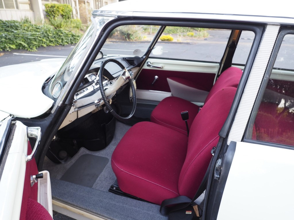 The interior of a white 1964 Citroen DS19, showing red seats and the push-button brake pedal