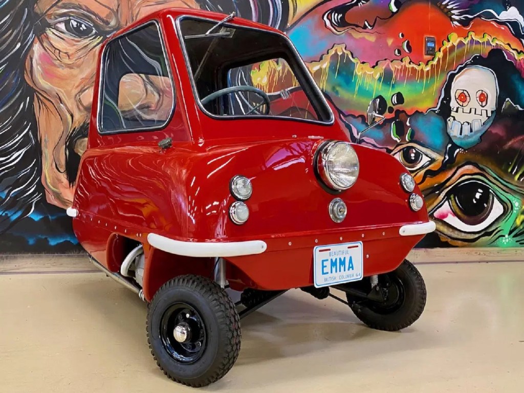 Red 1964 Peel P50 in front of a painted mural