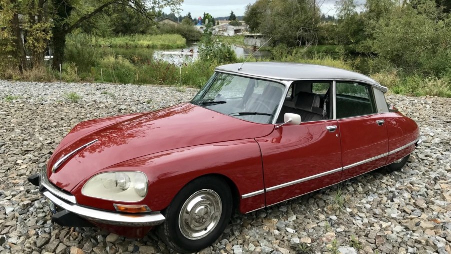 A red 1975 Citroen DS Pallas parked on a gravel forest road