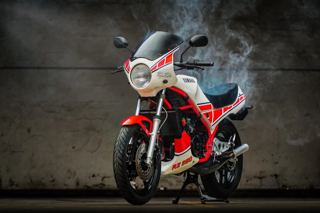 Red-and-white 1985 Yamaha RZ350 Kenny Roberts Edition with 2-stroke smoke wafting around it