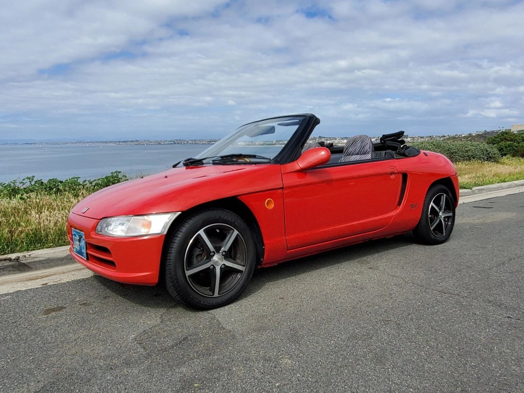 Red 1991 Honda Beat viewed from the side with the roof down