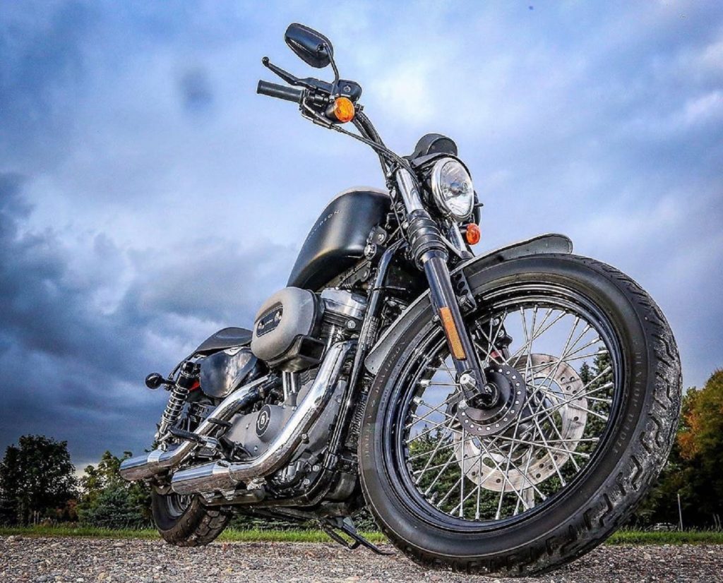 Low-angle shot of a black 2007 Harley-Davidson Sportster 1200 Nightster silhouetted against a cloudy sky