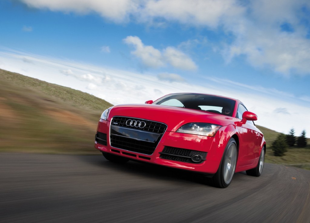 A low-angle shot of a red 2008 Audi TT Coupe driving down a road