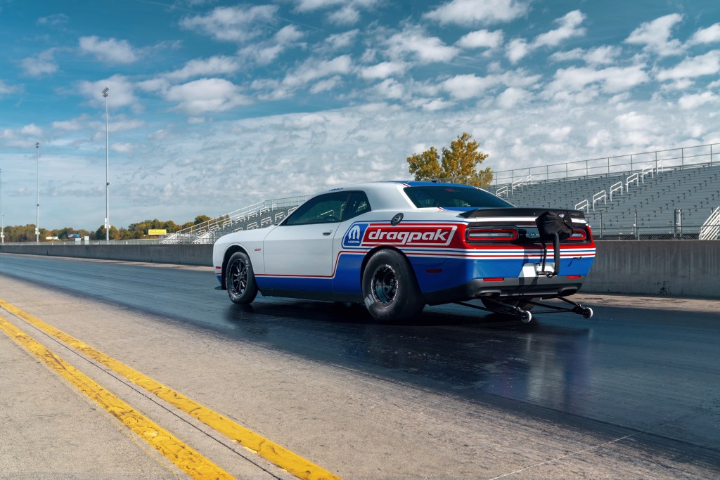 Rear view of the red-white-and-blue-liveried 2020 Dodge Challenger Drag Pak on a drag strip, showing the rear-mounted wheelie kit