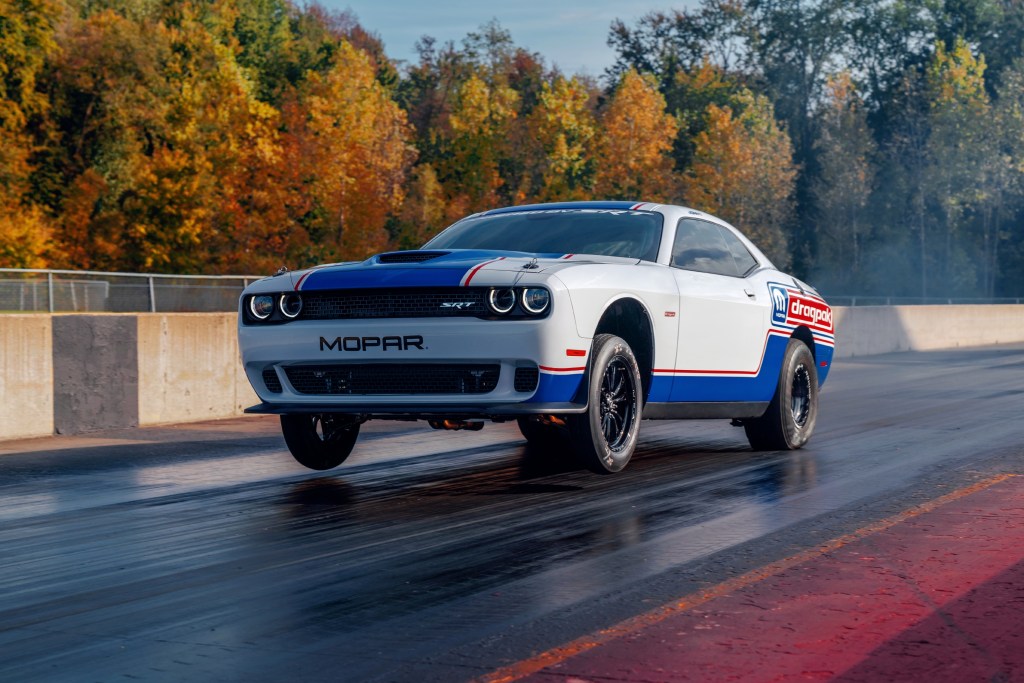 Red white and blue liveried 2020 Dodge Challenger Drag Pak pulling a wheelie racing on the drag strip