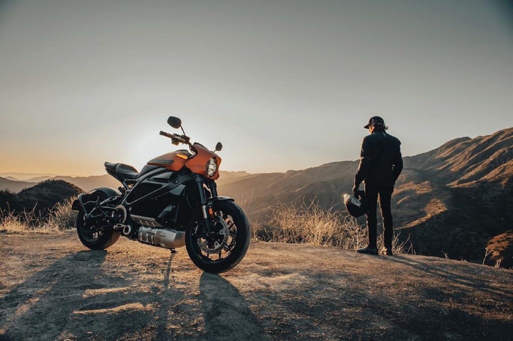 Orange 2020 Harley-Davidson LiveWire with its rider in the background, both watching the rising sun over a canyon