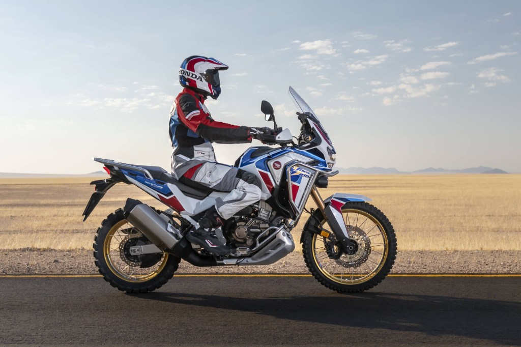 White-blue-and-red-liveried 2020 Honda Africa Twin Adventure Sports, side view, driving down a desert road