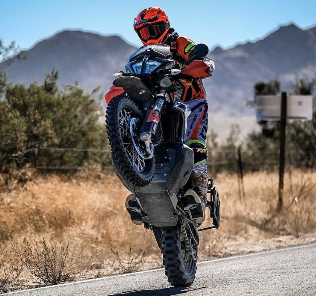 A rider wheelies a 2020 KTM 790 Adventure R, showing the Black Dog Ultimate skid plate