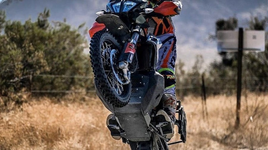 A rider wheelies a 2020 KTM 790 Adventure R, showing the Black Dog Ultimate skid plate