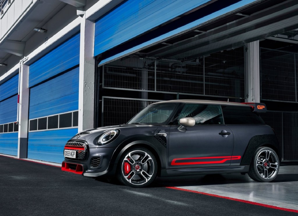 A black-and-red 2020 Mini Cooper JCW GP coming out of a blue track-side garage. More powerful than a Honda Civic Type R and Hyundai Veloster N