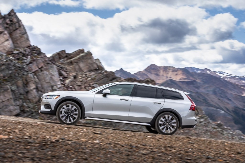 A white 2020 Volvo V60 sits at the foothillls of a mountain range.