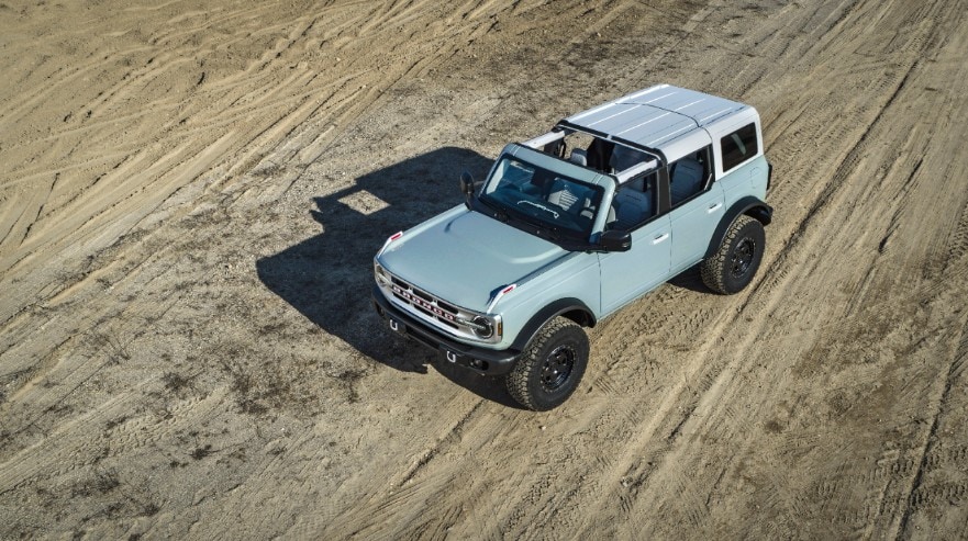 overhead light blue 2021 Ford Bronco with front roof removed bombing through the desert