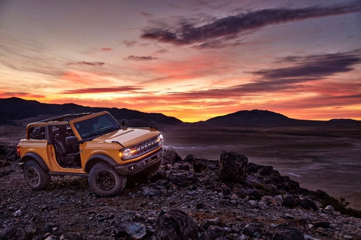 yellow 2021 Ford Bronco with front roof and doors removed bombing through the desert