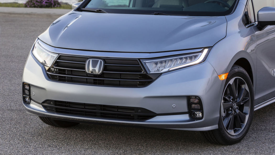 The front quarter of the driver front on a silver 2021 Honda Odyssey minivan.