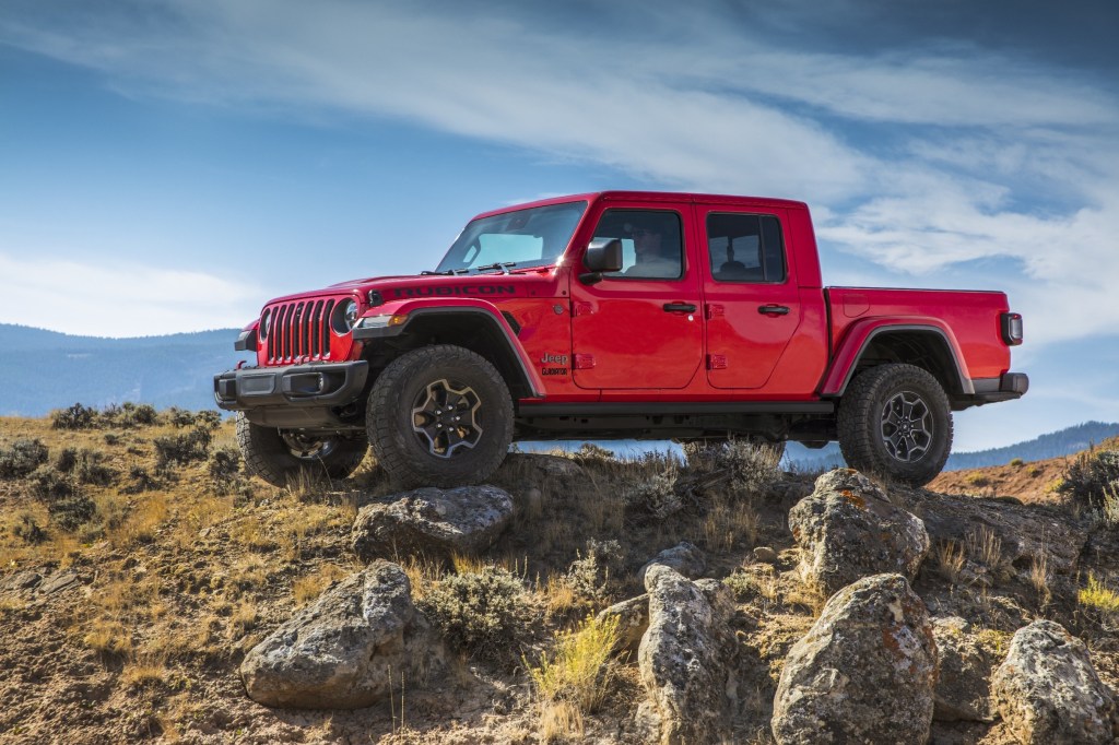 A red 2021 Jeep Gladiator sits atop of rocks. Jeep is part of the family of FCA brands.