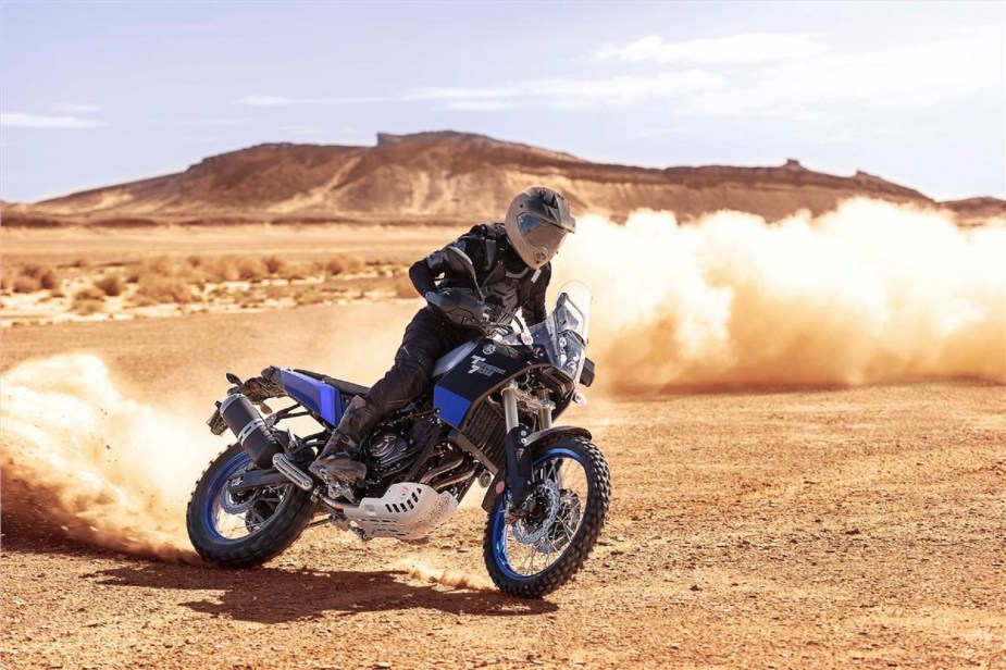 A blue-tanked 2021 Yamaha Ténéré 700 adventure bike power-sliding in the desert