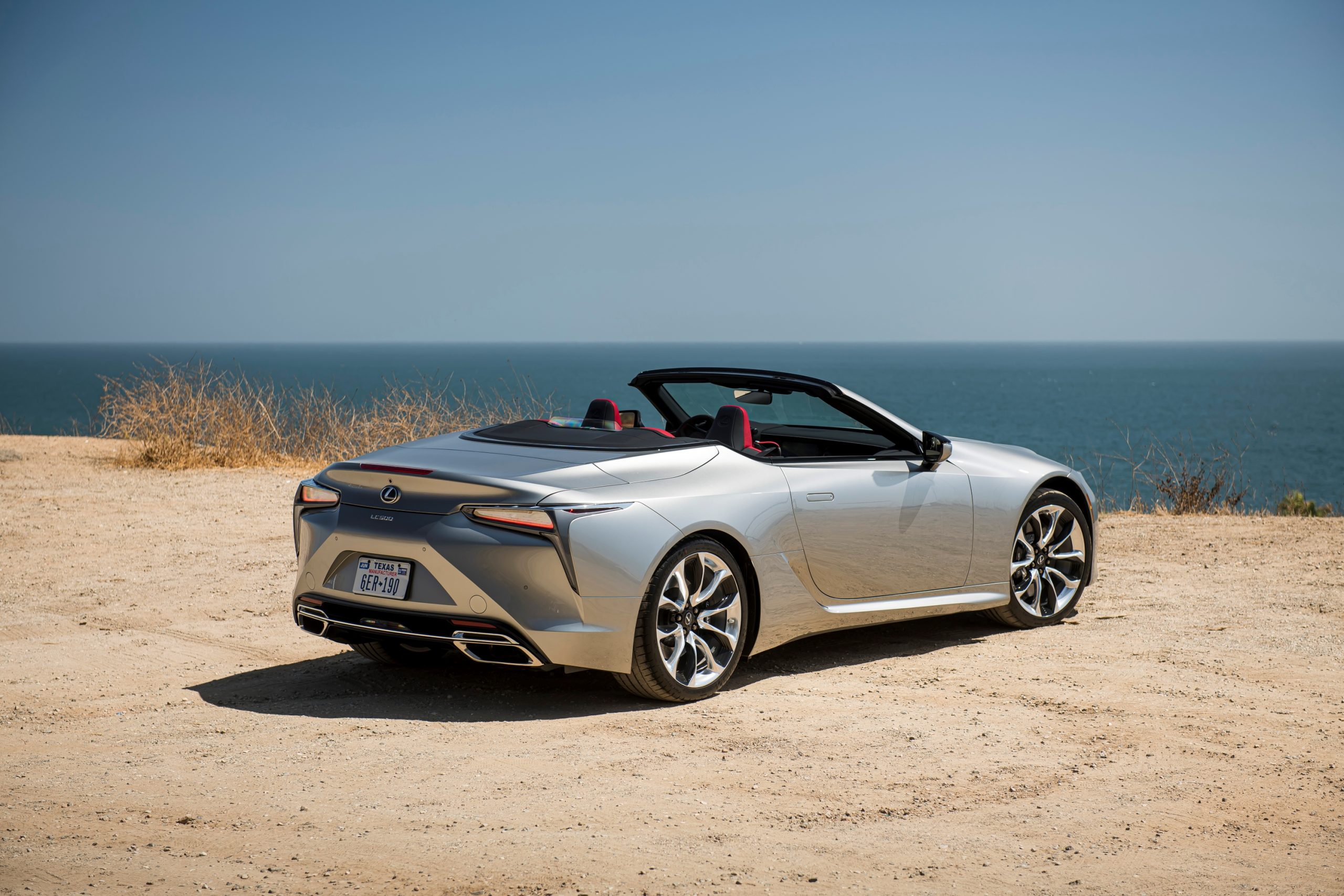 A silver 2021 LC 500 Convertible sits at a beach with the top down | Lexus