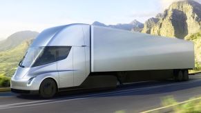 This is a rendering of a silver Tesla Semi tractor trailer on a road along a mountain pass.