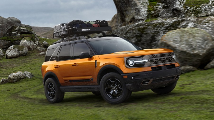 The 2021 Ford Bronco, the SUV sibling of the Ford F-150, in cyber orange off-roading in the wilderness