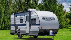 a GulfStream Coach RV trailer in a green lawn with a pleasant forested backdrop