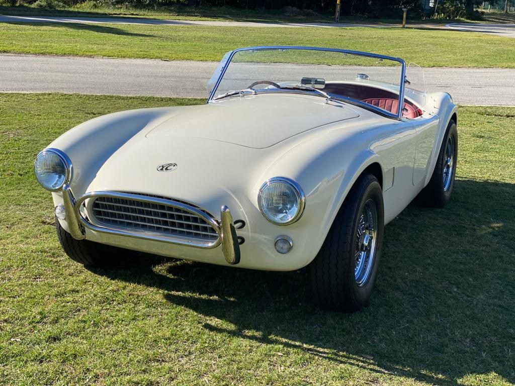 A new white AC Cobra Series 1 Electric car sits on a lawn. 