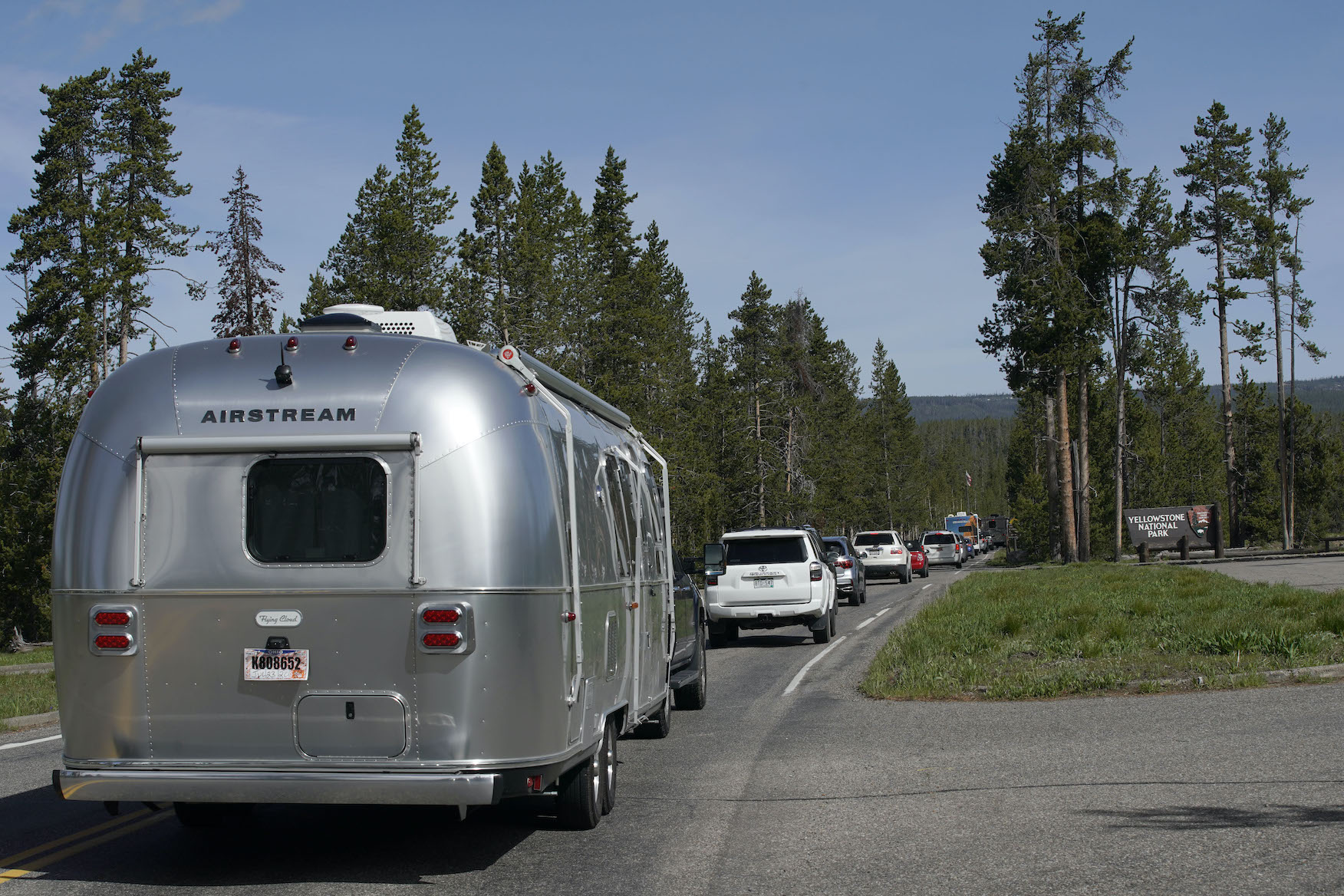 An Airstream RV trailer along with others, wait in a long line to enter the south entrance to Yellowstone National Park