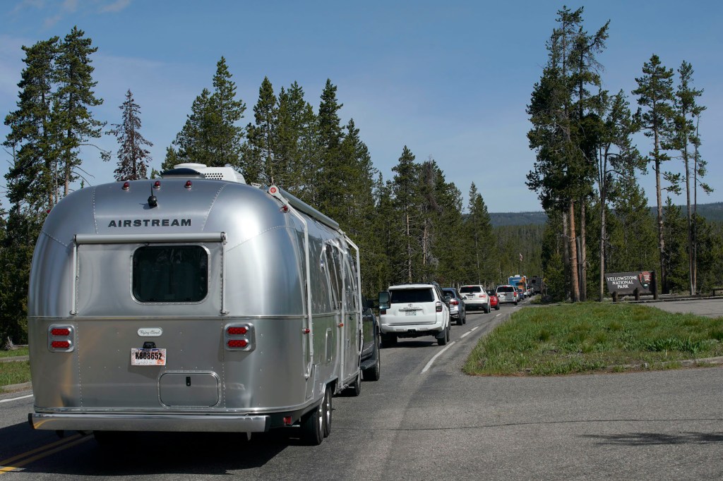 An Airstream RV trailer along with others, wait in a long line to enter the south entrance to Yellowstone National Park