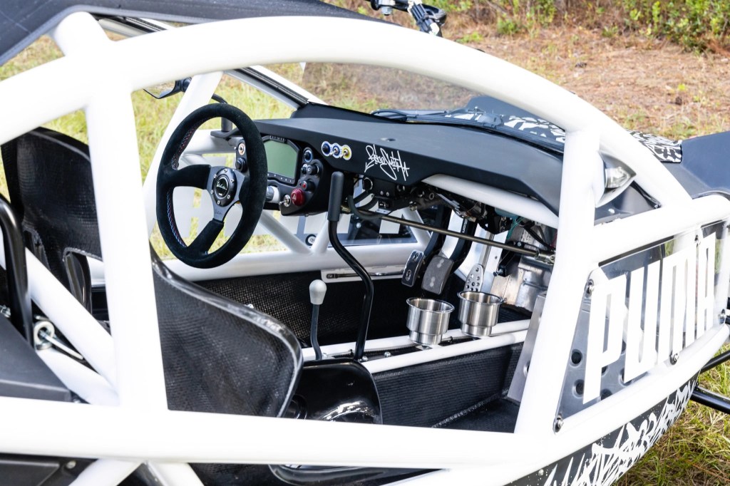 The cabin of the Ariel Nomad Tactical, showing the steering wheel, pedals, and seats