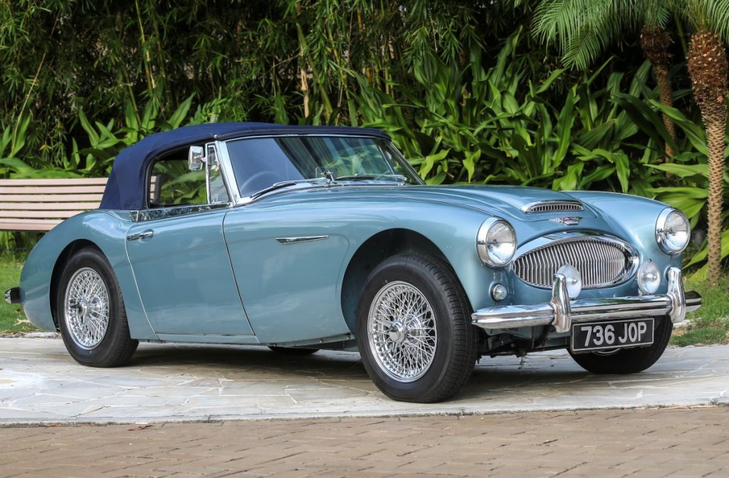 A sky-blue Austin-Healey convertible sits on display at a car show. 