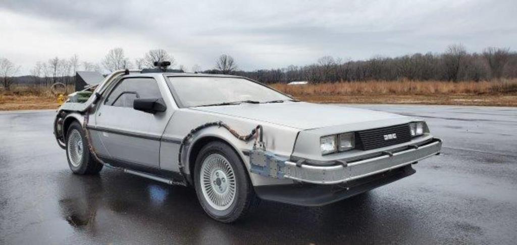 The Back to the Future replica Delorean movie car sitting in a wet parking lot.