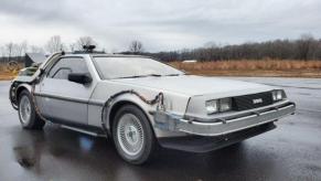 The Back to the Future replica Delorean sitting in a wet parking lot.