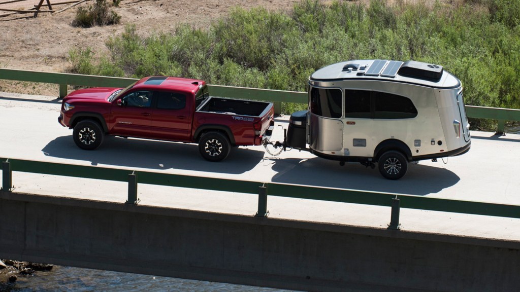 The Airstream Basecamp travel trailer is pulled behind a red Toyota pickup.