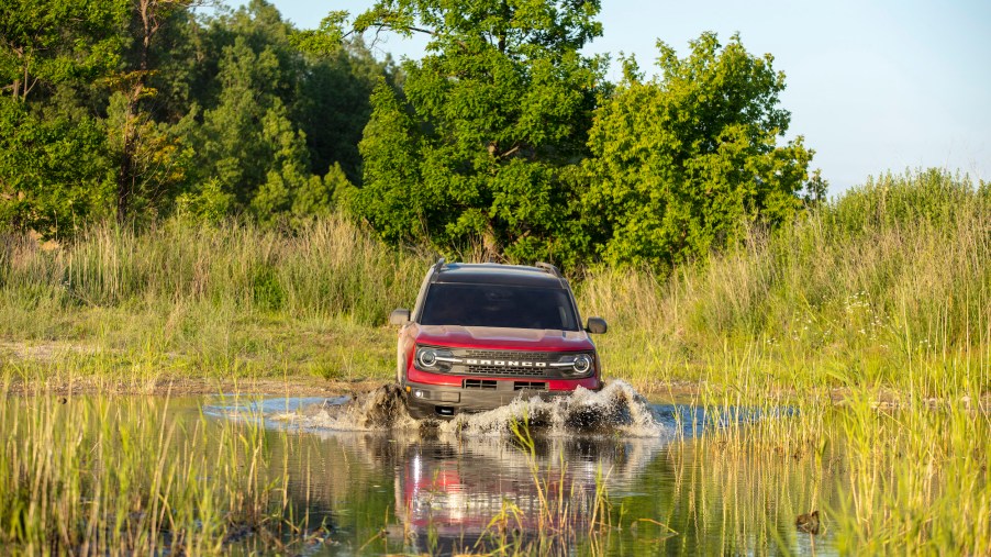 The Ford Bronco Sport, like this red one fording a deep puddle, is wild enough for most climbers