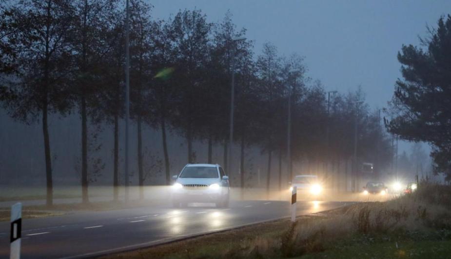 Cars with LED headlights driving on a foggy road.
