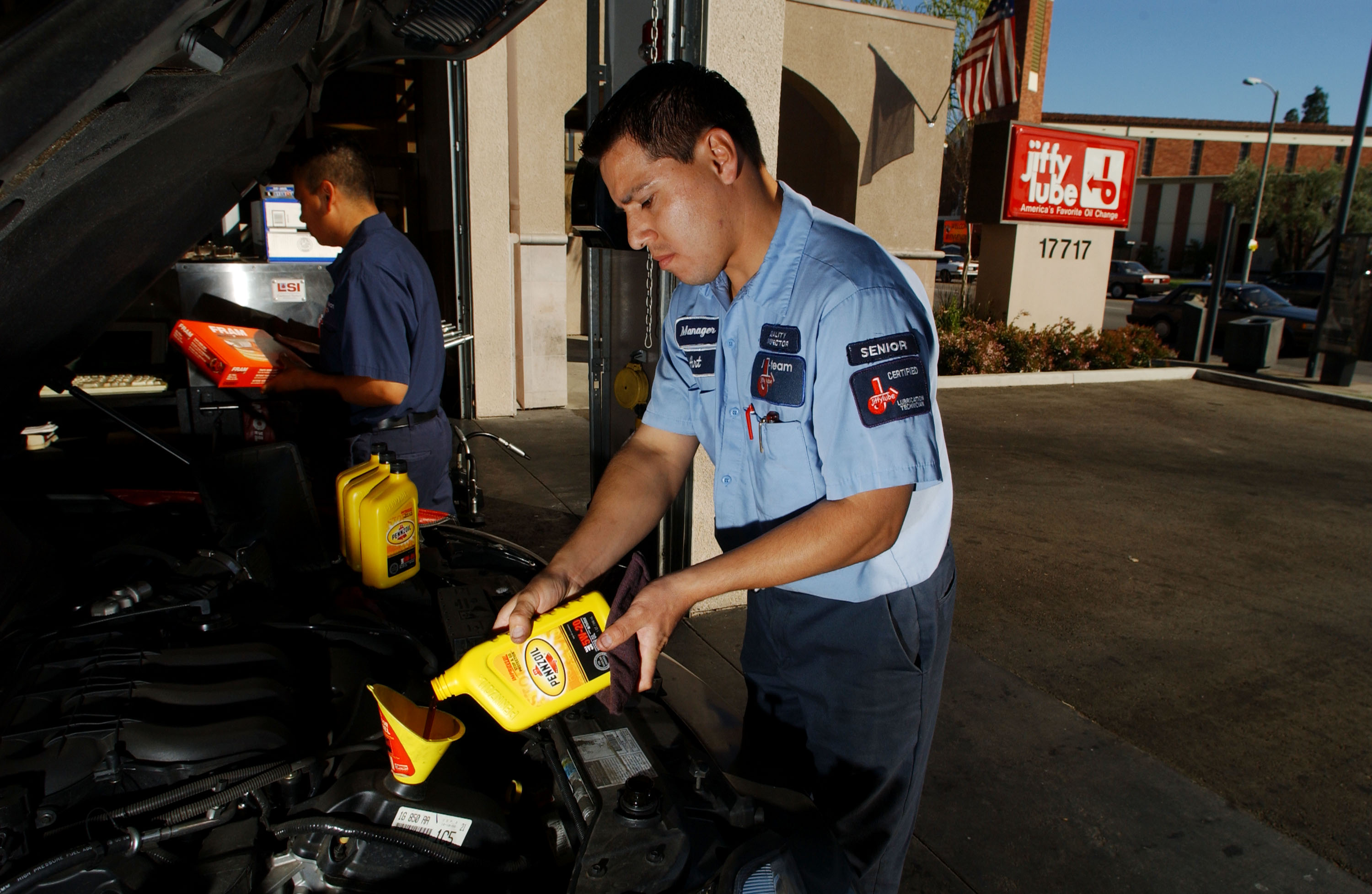 A man pours a new bottle of oil into a car