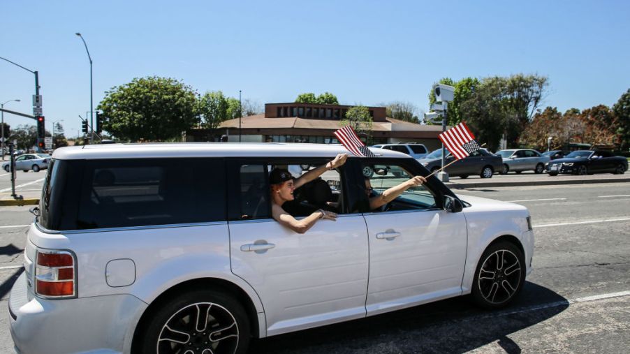 waving American flags from a Ford Flex on the highway