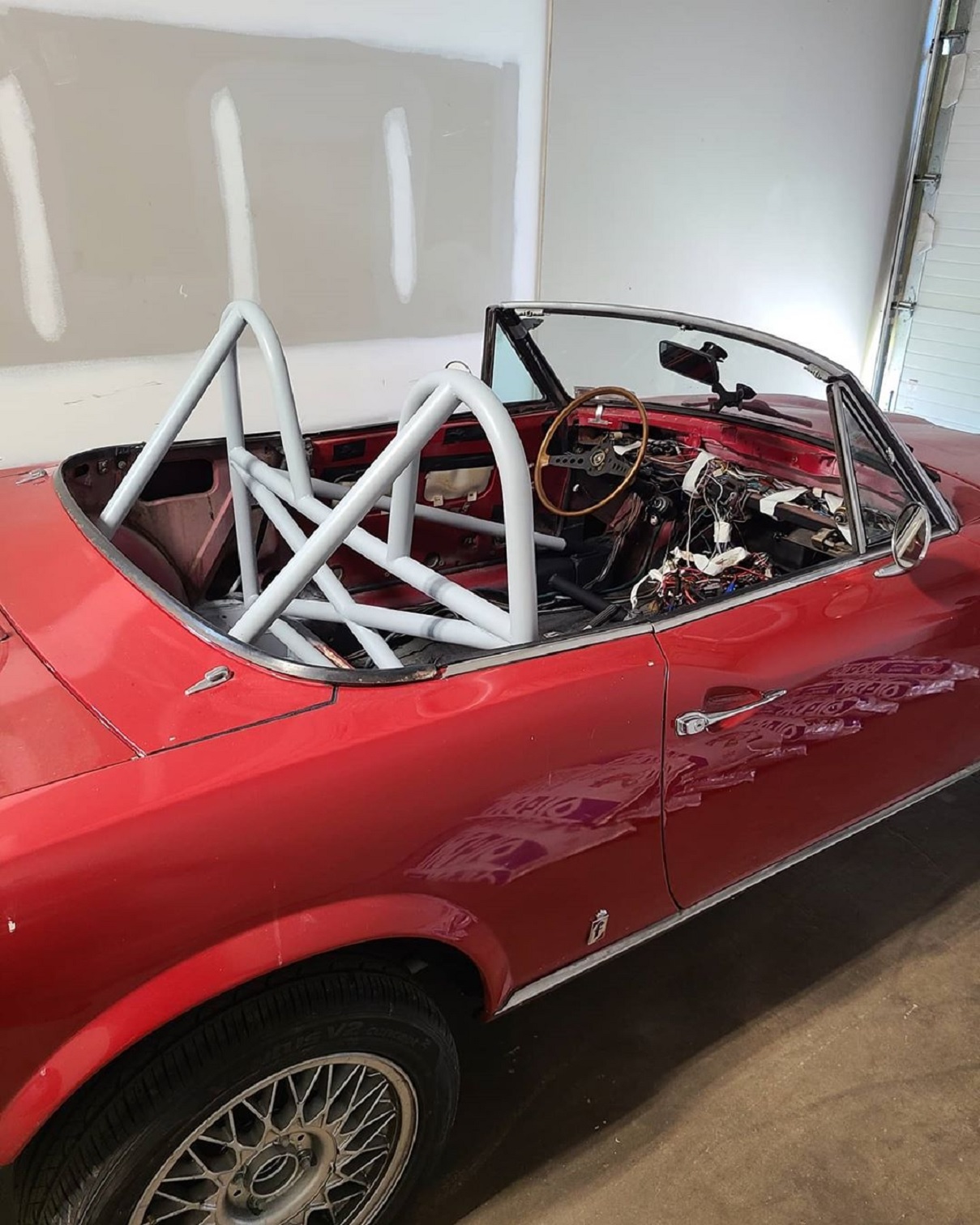 Red 1970s Fiat Spider with a white 4-point roll bar installed
