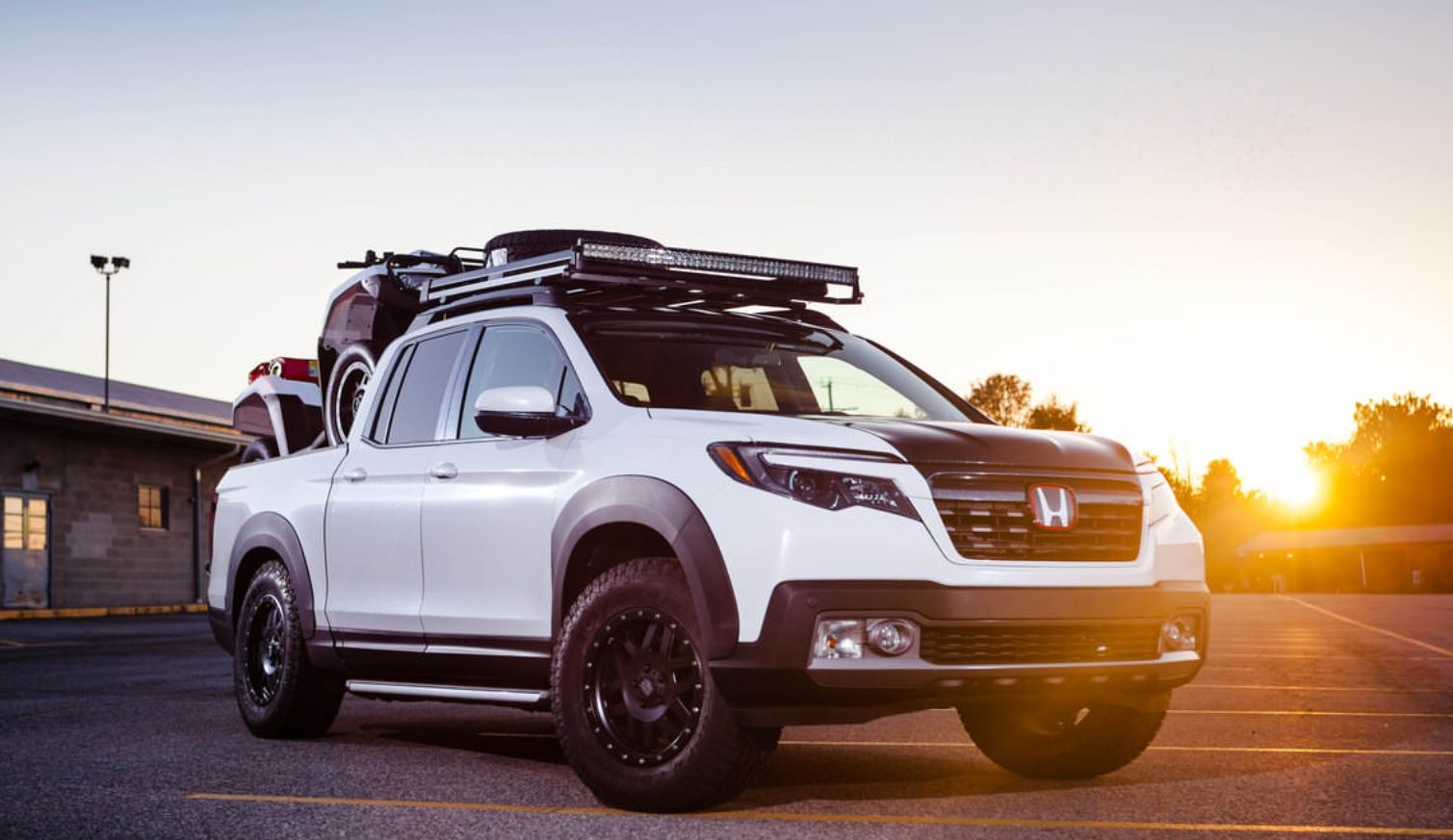 A custom white Honda Ridgeline has had some offroad upgrades, like fender flares, a roof rack, and a lift kit.
