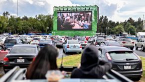 Two people stick their head out the sunroof to watch a drive-in movie