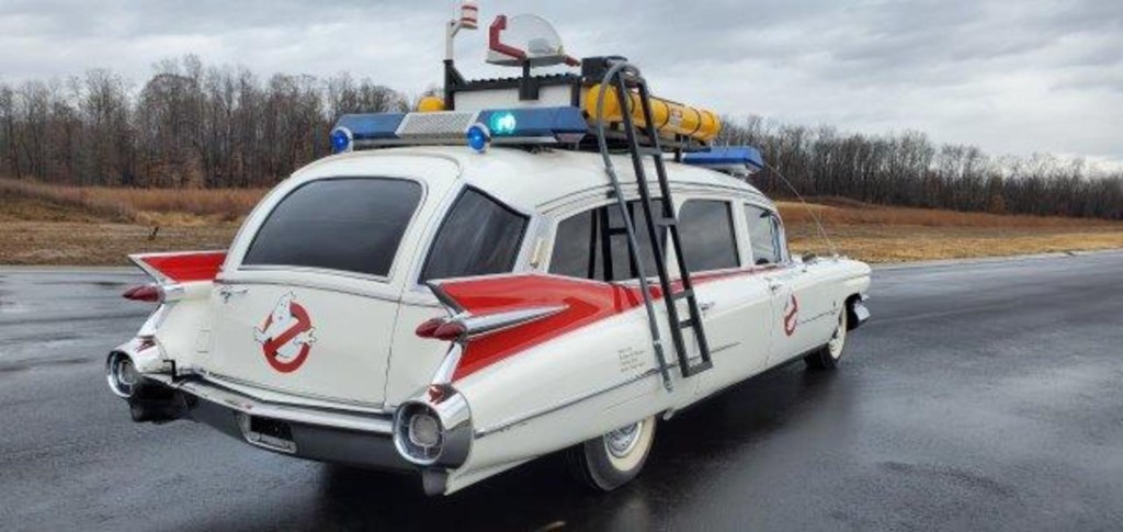 The passenger side rear of the Ecto-1 Cadillac sitting in a wet parking lot.