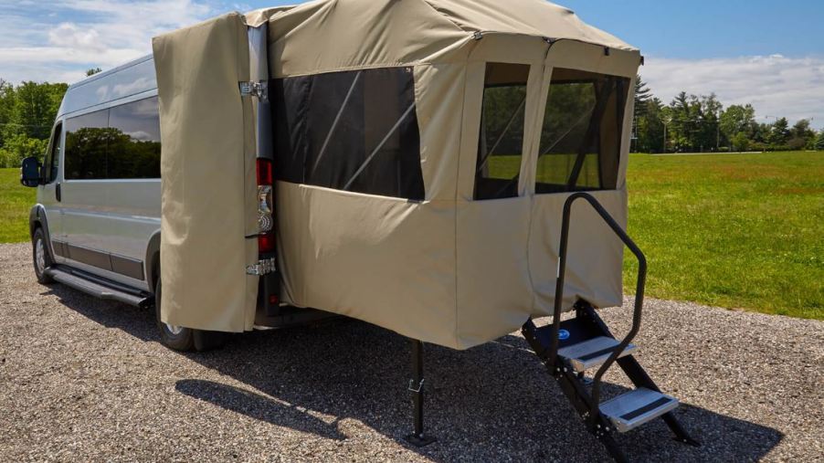 The rear of an RV has a porch tent platform.