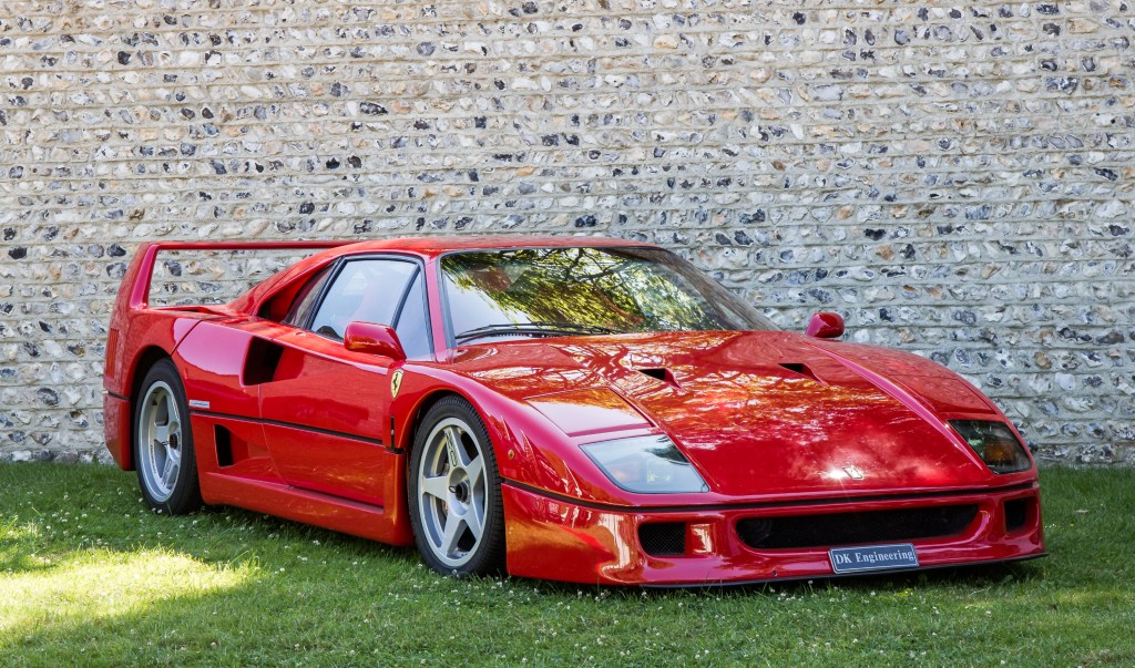 A red Ferrari F40 sits on the grass on display at a car show. 