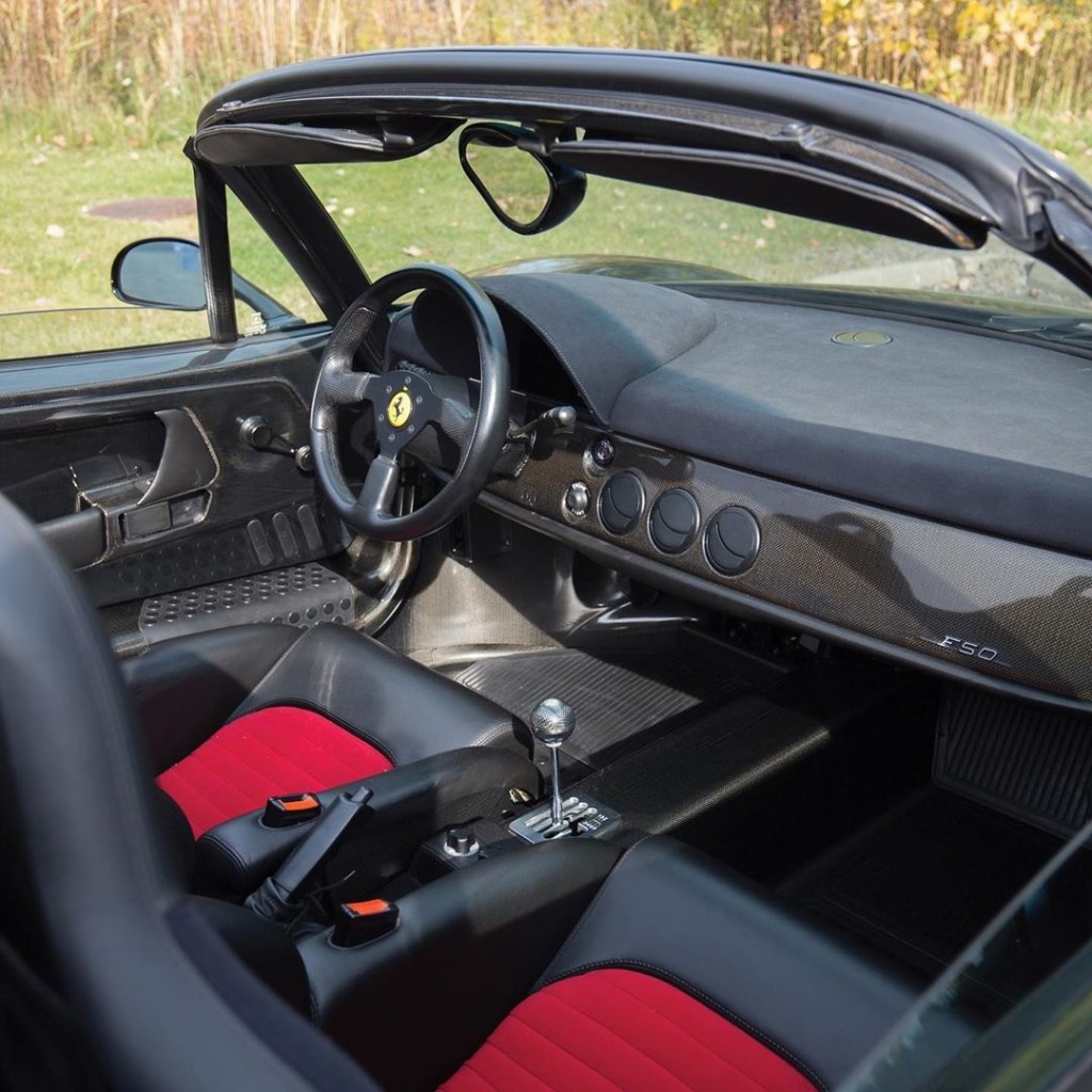 Interior shot of the Ferrari F50, showing the exposed carbon fiber, red-insert sport seats, and gated manual