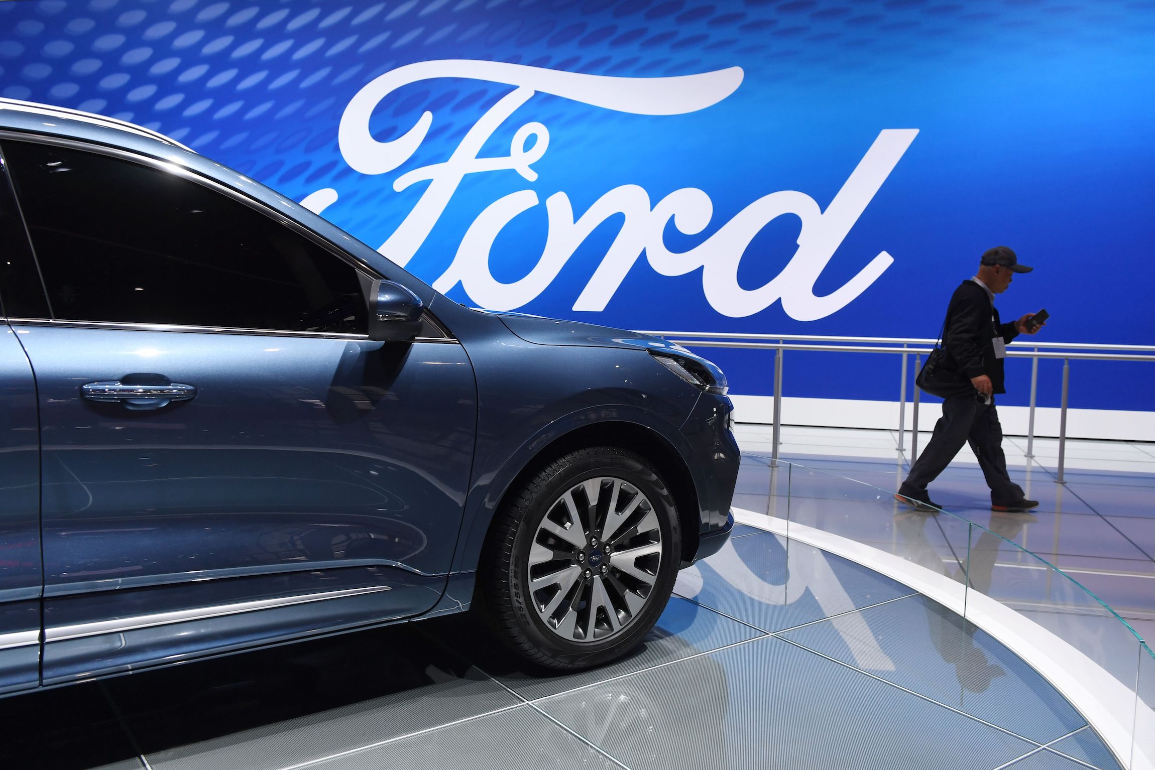 A visitor walks past a Ford Escape Titanium at the Shanghai Auto Show