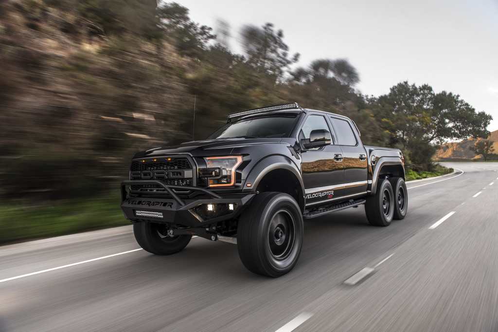 A black Hennessey Velociraptor 6x6 pickup on the road.
