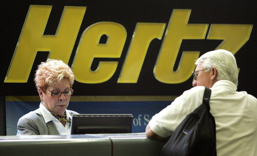 A customer is at the Hertz counter discussing a rental with an employee