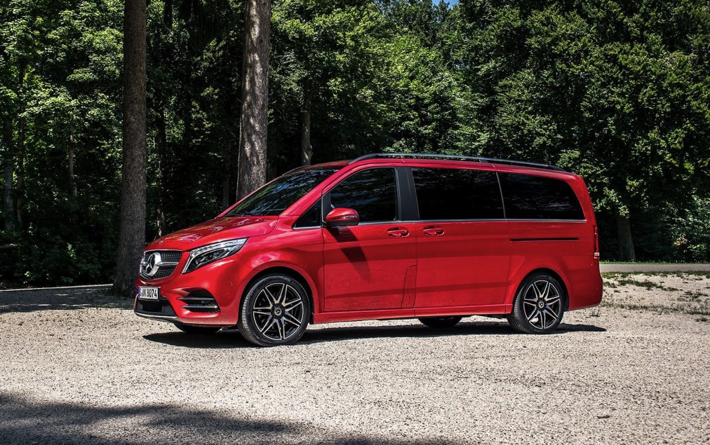 red mercedes minivan with a forested backdrop