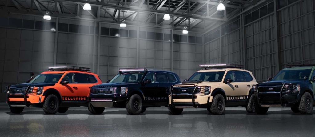 Four off-road ready modified Kia Telluride models are parked side by side. 